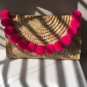 Straw clutch with magenta pompoms